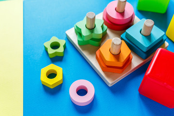 Wooden kids toys on colourful paper. Educational toys blocks, pyramid. Toys for kindergarten, preschool or daycare. Copy space for text. Top view	