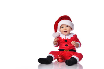 Little child boy toddler in santa claus christmas costume and hat happy smiling with red gift ball fir decoration ready to celebrate