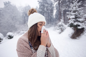 Woman blowing her nose at winter day