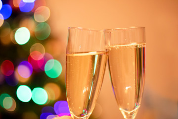 Blurred christmas tree and two glasses with sparkling wine champagne. New Year concept