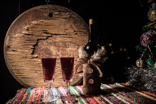 Red wine in crystal glass with bottle on colorful carpet with creative New Year artwork decorations. Copy space