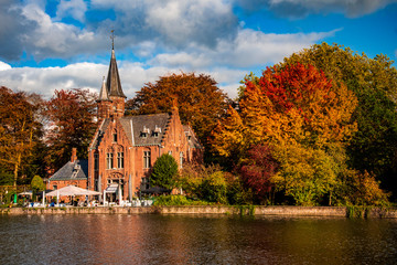 Reflections of autumn trees across Minnewater in Bruges