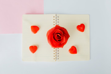 Four love candies and a rose placed on notebook