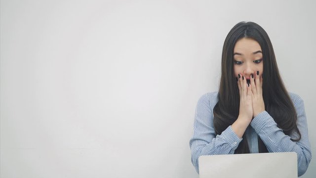 Amazed asian lady sitting on the floor with laptop, covering her mouth by a hands surprised with something.
