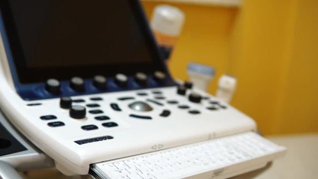 Zoom in on ultrasound scans, specialty medical equipment, bright keyboard and dark monitor, device off