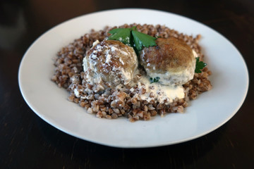 two cutlets with buckwheat porridge, poured with sauce on a white plate