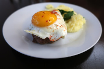 beef steak with egg and mashed potatoes on a white plate in a restaurant