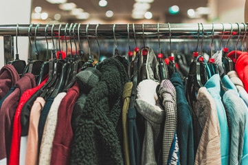 Colourful clothes on hangers. Close up picture of clothes hanged in a shop or at home. Colourful textured fabrics.