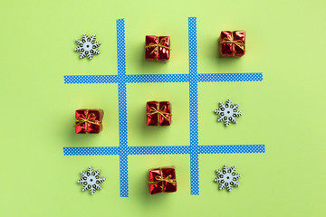 Tic tac toe game with christmas toys, isolated on green background. Christmas, winter concept. Flat lay, top view.