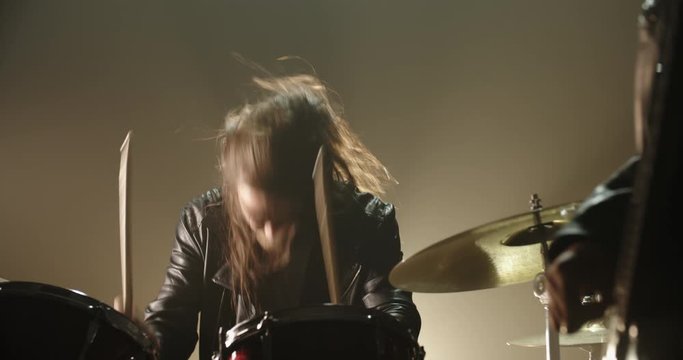 Cool drummer is playing in band, hitting the drums real hard during solo in performance in club - rock band music concept 4k footage