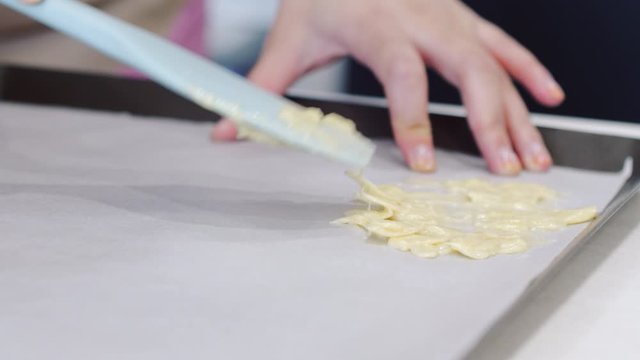 Young woman spreads out almond biscuit batter