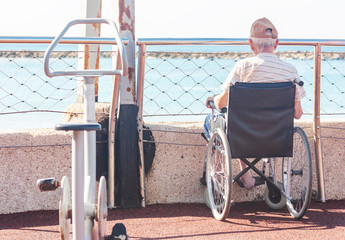 An old man in a wheelchair on the sports ground