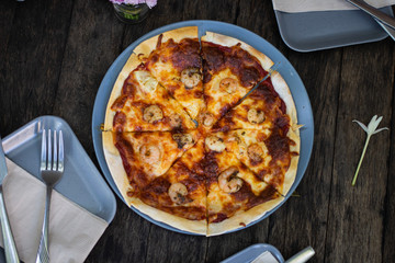 Pizza on wood table with dish top view