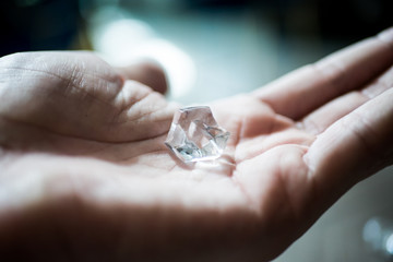 Male hand holding shiny diamond.