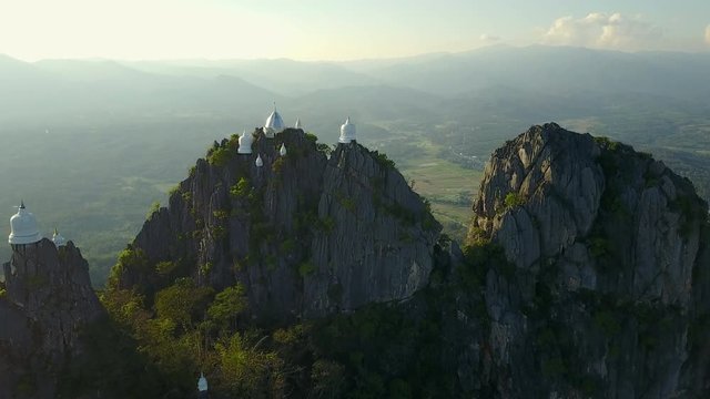 Spectacular aerial view of floating pagodas on the mountain cliff at Wat Chaloem Phra Kiat in Chae Hom District, Lampang province, Thailand. 4K drone video