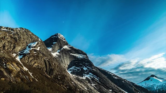 National Mountain of Norway Stetind (1.392 moh)Time lapse blue sky with half moon rootating. Snow falling from the peak. Stetind is considered the highest granite obelisk on earth.