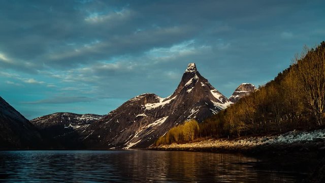 National Mountain of Norway Stetind (1.392 moh), by the water time lapse of the snowy peak of Mountain blue clouds in Tysfjord.