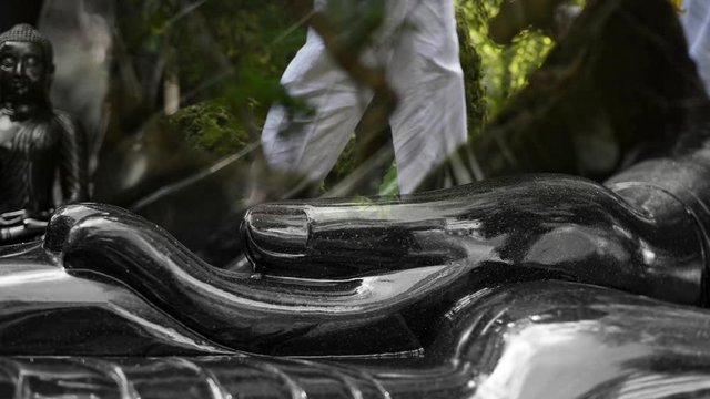 Mindfulness walking for Dhamma practitioners in the temple superimposed with a hand of black sitting Buddha image. Reflecting every breath in every step in life for a meditation practice.