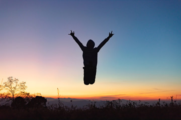 Silhouette of happy people jumping playing on mountain at sunset