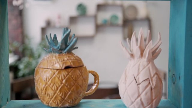 closeup shot of two hipster pineapple fruit shaped pottery cup pot in a workplace of potter. pottery handicrafts on background. concept business, creative, nobody concept.