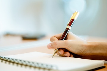 close up female hands with pen writing on notebook, consept learn and plan.