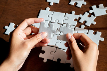 Hands holding jigsaw puzzle, conceptual of problem solving, finding a solution, planning.