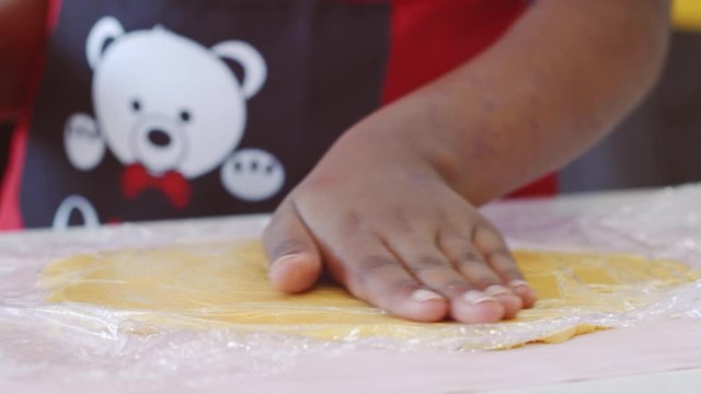 Young girl smoothes pastry dough with hands and rolling pin