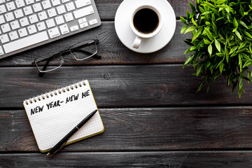 New year new me motto - motivation concept. Notebook for writing goals and plans on dark wooden office desk top-down copy space
