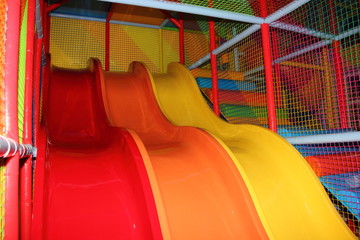 Big empty colored children's slides  with springboard and soft net safety walls close up in kids Park