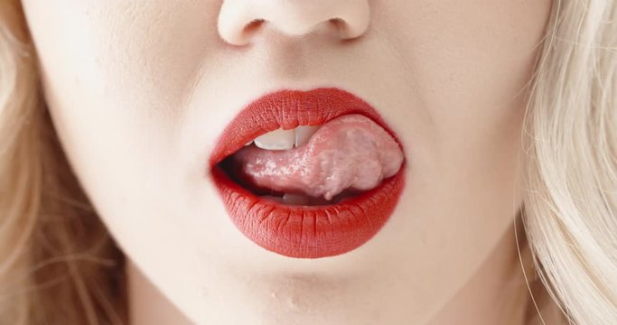 Close up shot of sensual blonde girl seductively licking and biting lips with bright red lipstick 4k footage