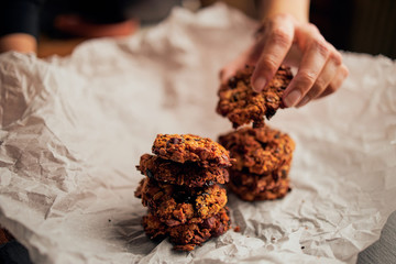 Close up of hand serving freshly baked breakfast cookies on baking paper	
