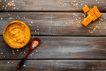 Trendy dessert - salted caramel - melted and cubes on dark wooden background top view frame copy space