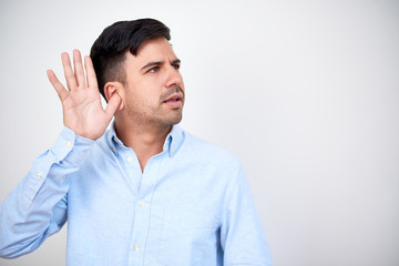 Young businessman holding hand near ear when eavesdropping rumors