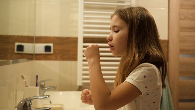 After washing hands cute kid girl play make soap bubbles in bathroom in front of mirror having fun in pajamas in the morning