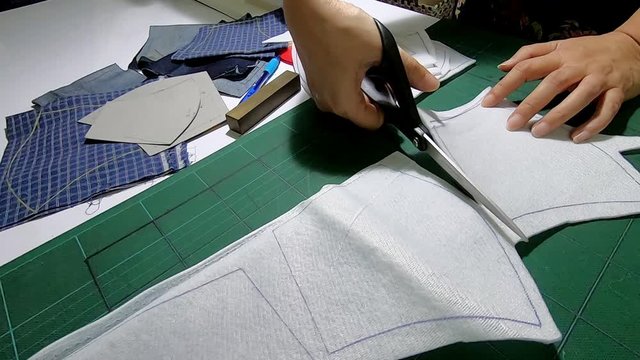 Woman doing her patchwork using scissor cutting the pattern of product - lady house work footage concept