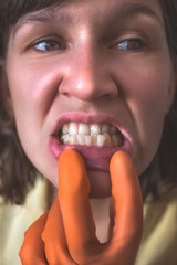 Woman in gloves shows her crooked teeth.