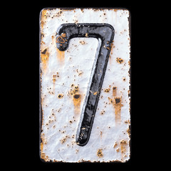 Number 7 made of forged metal on the background fragment of a metal surface with cracked rust.
