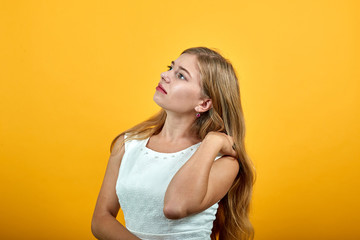 Caucasian blonde young woman looking aside, holding hand on shoulder over isolated orange...