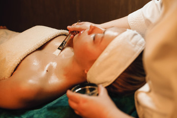 Beautiful female relaxing while having a transparent facial and body mask in spa salon.