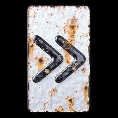 Symbol right pointing double angle quotation mark made of forged metal on the background fragment of a metal surface with cracked rust.