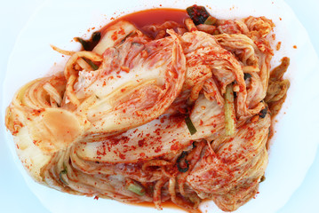 Traditional korean kimchi cabbage on a white plate close-up top view.