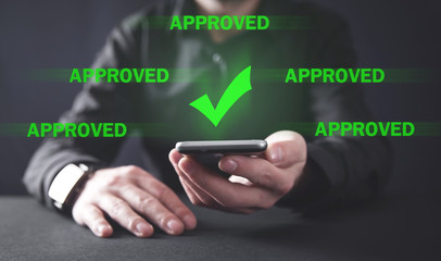 Businessman holding smartphone with a check mark. Approved