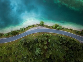 Beautiful aerial view of road between green summer forest and blue lake in Austria,Europe,Plansee lake.