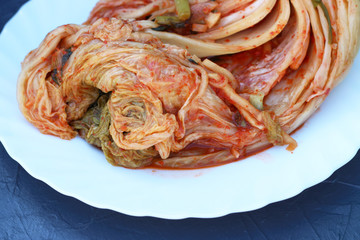 Traditional korean kimchi cabbage on a white plate close-up.