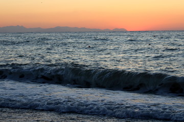 the sun setting behind the promontory with the sea in the foreground