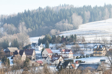 Fototapeta na wymiar PIENIAZKOWICE, POLAND - DECEMBER 06, 2019: View of the village houses situated on the hills on a foggy winter morning.