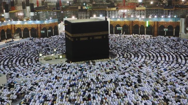 Muslim pilgrims bow and prostrate during evening prayer facing the black stone (or Kaaba) in Mecca, Saudi Arabia.