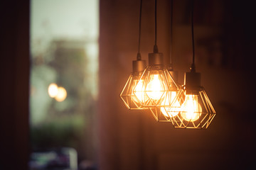 Lightning lamps at home, in restaurant or cafe: Close up of a hanging, orange lightbulbs - 309894157