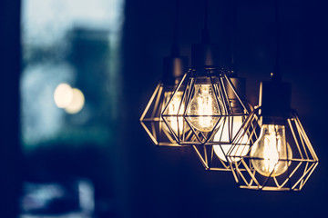 Fototapeta na wymiar Lightning lamps at home, in restaurant or cafe: Close up of a hanging, orange lightbulbs