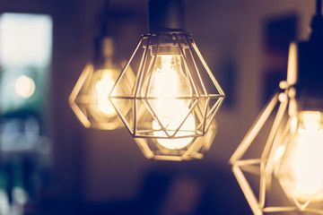 Obraz na płótnie Canvas Lightning lamps at home, in restaurant or cafe: Close up of a hanging, orange lightbulbs